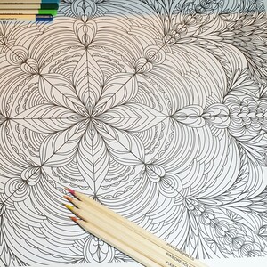 May include: A black and white intricate mandala design coloring page with a set of colored pencils on top of the page. The pencils are wooden and have a natural finish.