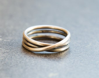May include: A silver ring with a twisted design. The ring is made of three bands that are intertwined.