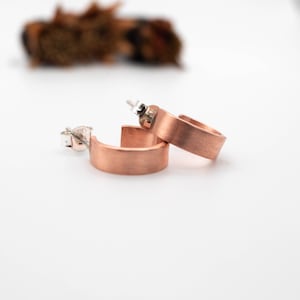 Puede incluir: Un par de pendientes de aro de oro rosa cepillado. Los pendientes son simples y elegantes, con un acabado liso y mate.