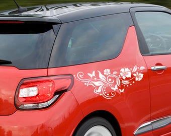 May include: A red car with a black roof and a white floral design on the side. The car has a number plate that reads "RV59 GZA".