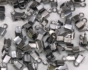May include: A pile of silver-toned metal clasps with a small loop on each one. The clasps are designed to be used for jewelry making or other craft projects.