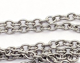 May include: A silver chain with oval links. The chain is lying on a white surface.