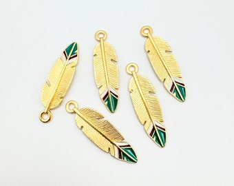 May include: Five gold-colored metal feather charms with green, white, and burgundy enamel accents. The charms have a loop at the top for attaching to jewelry or other crafts.