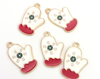 May include: Five gold-tone metal charms shaped like mittens with a white enamel finish and a green and white snowflake design. The mittens have a red enamel cuff.