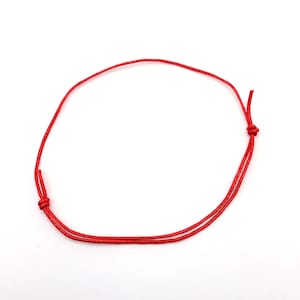May include: A red string bracelet with a simple knot fastening.