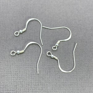 May include: Four silver earring hooks with a small ball at the top of each hook.