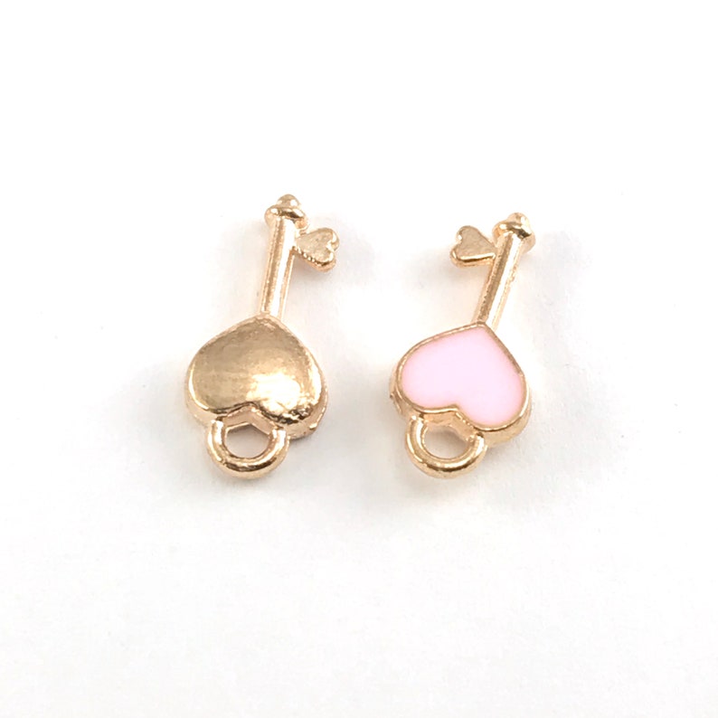May include: Two gold-colored key charms with heart-shaped heads. One charm has a gold heart, and the other has a pink heart.