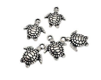 May include: Five silver turtle charms with a detailed textured shell design. The charms are perfect for jewelry making or adding a touch of whimsy to crafts.