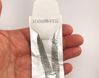 May include: A silver chain necklace packaged on a white card with the text "Stainless Steel".