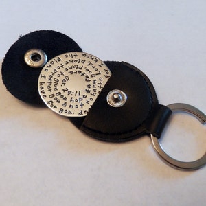 May include: A silver keychain with a black leather pouch. The keychain has a round metal disc with the text "For I know the plans I have for you, plans to prosper you and not to harm you, plans to give you hope and a future." The text is written in a cursive font.
