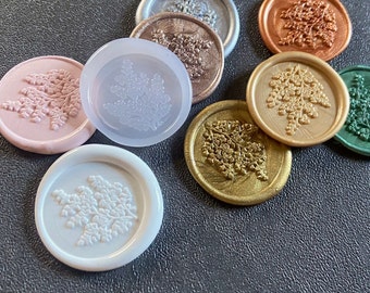 Puede incluir: Surtido de sellos de cera con un diseño floral. Los sellos son de varios colores, incluyendo rosa, blanco, dorado, cobre y verde.