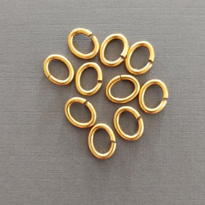 以下が含まれることがあります： 灰色の表面に、10個の金色の楕円形のジャンプリングが緩い円形に配置されています。