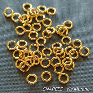 Peut inclure: Un grand tas de anneaux de saut dorés. Les anneaux sont tous de la même taille et sont en métal. Ils sont parfaits pour la fabrication de bijoux ou d'autres travaux manuels.