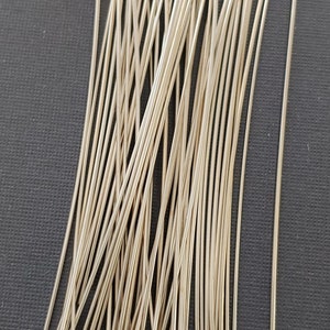 May include: A bunch of silver head pins with a flat head. The pins are about 2 inches long and are arranged in a random pattern.