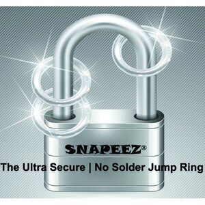 Puede incluir: Un candado plateado con dos anillos de salto plateados alrededor del grillete. El candado tiene el texto "SNAPEEZ&reg;" y "The Ultra Secure | No Solder Jump Ring" en el cuerpo.