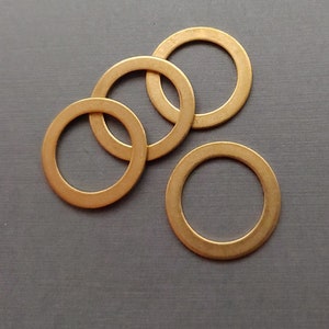 May include: Four gold-coloured metal washers on a grey surface. The washers are circular with a hole in the centre. The text "Via Murano" is in the bottom right corner.