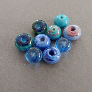Bead lot of 9 American made lamp worked blue glass beads approximately 10 to 11mm in diameter. Made in USA.