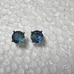May include: A pair of silver stud earrings with round, faceted, blue-green gemstones.