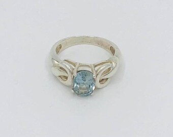 May include: A silver ring with a light blue oval gemstone set in a delicate, twisted band.