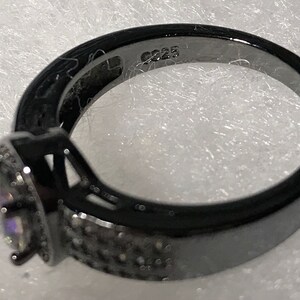May include: Black ring with a square-shaped center stone and a band of small black stones. The ring is marked with the number "925" on the inside of the band.