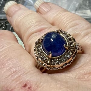 May include: A gold ring with a large oval blue gemstone surrounded by smaller clear gemstones.