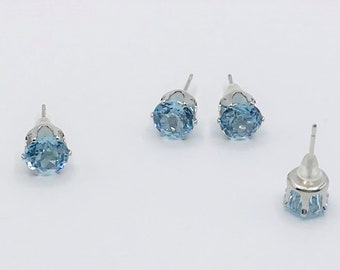 May include: A pair of silver stud earrings with light blue round gemstones.