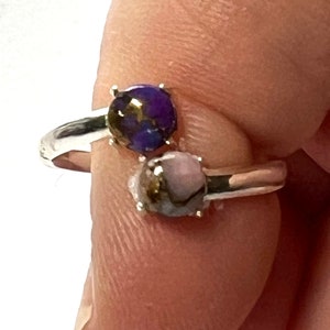 May include: A silver ring with two round stones. The stones are a purple and a pink color with gold flecks.