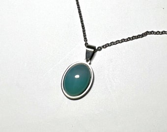 May include: A silver chain necklace with a light blue oval pendant. The pendant has a silver border and a smooth, polished surface.