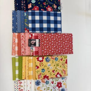 May include: Folded fabric squares in a variety of floral and patterned designs. Colours include navy, blue, red, yellow, and white. Patterns include gingham, polka dots, and floral prints. Suitable for quilting or craft projects.