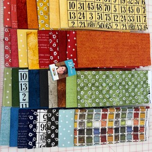 May include: A collection of rectangular fabric strips featuring various patterns including bingo cards, small white flowers on green and yellow backgrounds, solid colours in red and orange, and a grid of small coloured squares with text labels.