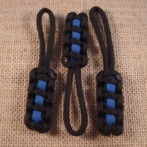 May include: Three black and blue paracord keychains with a loop at the top. The keychains are made with a woven pattern.
