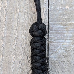 May include: Black rope dog toy with a knotted handle. The rope is braided and has a loop at the top.