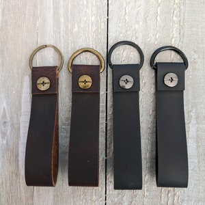 May include: Four leather keychains with metal rings and a screw-on button. The keychains are brown, dark brown, black, and black.
