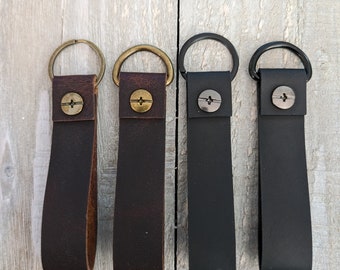 May include: Four leather keychains with metal rings and a screw-on button. The keychains are brown, dark brown, black, and black.