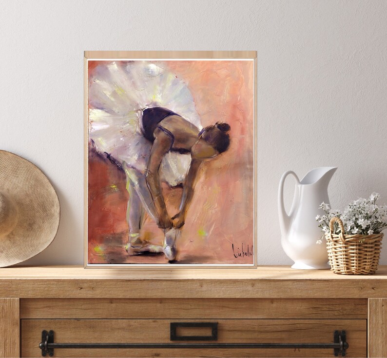 May include: A painting of a ballerina in a white tutu tying her ballet shoes. The background is a soft pink and orange.