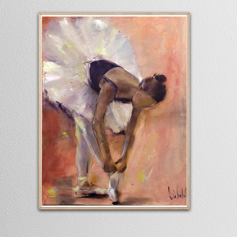 May include: A ballerina in a white tutu and black leotard is tying her pointe shoes. The background is a warm peach color.