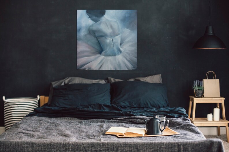 May include: A bedroom with a dark grey wall, a bed with black bedding, a painting of a ballerina in a white tutu, a bedside table with a small plant and a brown paper bag, and a black lamp hanging from the ceiling.