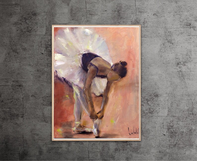 May include: A ballerina in a white tutu and black leotard is tying her pointe shoes. The background is a soft peach color.