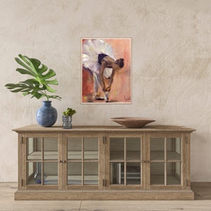 May include: A painting of a ballerina in a white tutu tying her ballet shoes. The background is a soft peach color.