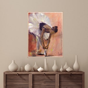 May include: A painting of a ballerina in a white tutu, tying her pointe shoes. The background is a soft peach color with hints of yellow.