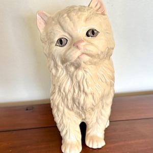 Puede incluir: Un letrero de madera hecho a mano con el texto "Bienvenido a nuestro hogar" en un estilo manuscrito. El letrero está pintado de blanco con un marco de madera teñida oscura. Un pequeño corazón decorativo está adjunto en la parte inferior.