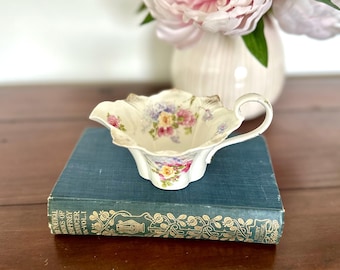 Jarra de crema de porcelana antigua con diseño floral y delicado borde festoneado.