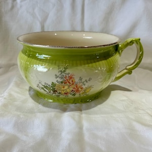 Könnte beinhalten: Eine Vintage-Keramikschale mit Henkel, hellgrün außen und cremefarben innen. Sie hat ein Blumenmuster in Gelb, Orange und Rot. Der Rand ist goldfarben. Durchmesser ca. 20 cm.