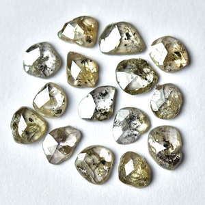 May include: A collection of 14 rough, unpolished, grey and green diamonds. The diamonds are various sizes and shapes, with some having a more rounded shape and others having a more pointed shape.