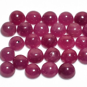 May include: A collection of 40 round, cabochon cut ruby gemstones. The rubies are a deep, rich red color and have a smooth, polished finish.