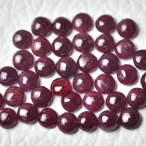 Pode incluir: Uma coleção de 30 pedras preciosas de rubi redondas cortadas em cabochão. Os rubis são de cor vermelha profunda e têm um acabamento liso e polido.