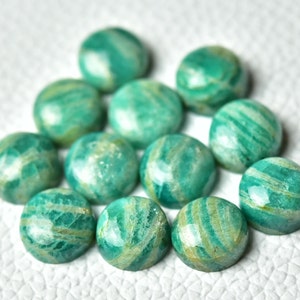 May include: A collection of 12 round, green and white amazonite cabochons. The cabochons are smooth and polished, with a variety of patterns and swirls.