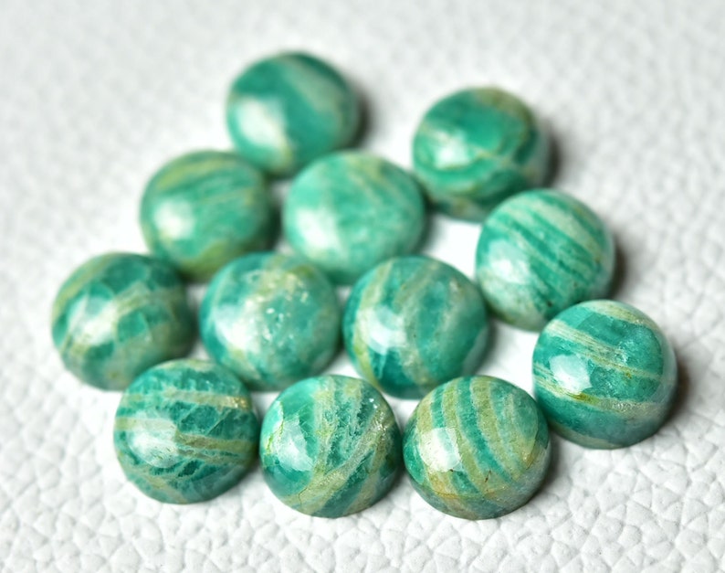 May include: A collection of 12 round, green and white amazonite cabochons. The cabochons are smooth and polished, with a variety of patterns and swirls.