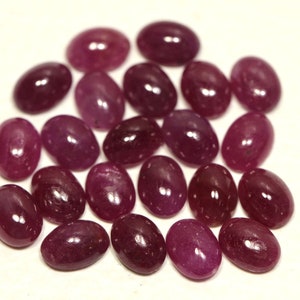 May include: A collection of 20 oval-shaped, faceted, ruby gemstones. The rubies are a deep, rich red color and have a high polish.