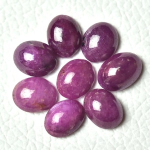 May include: Eight oval-shaped gemstones with a purple hue. The gemstones are smooth and polished, with a glossy finish.